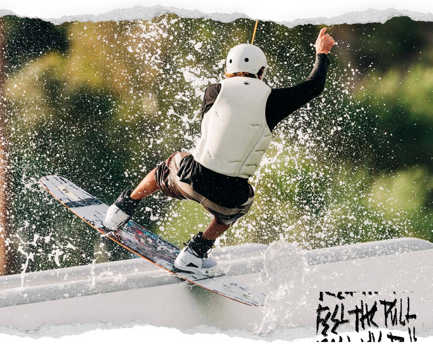 Rider wakeboarding in white vest, hitting a rail with water spraying behind.