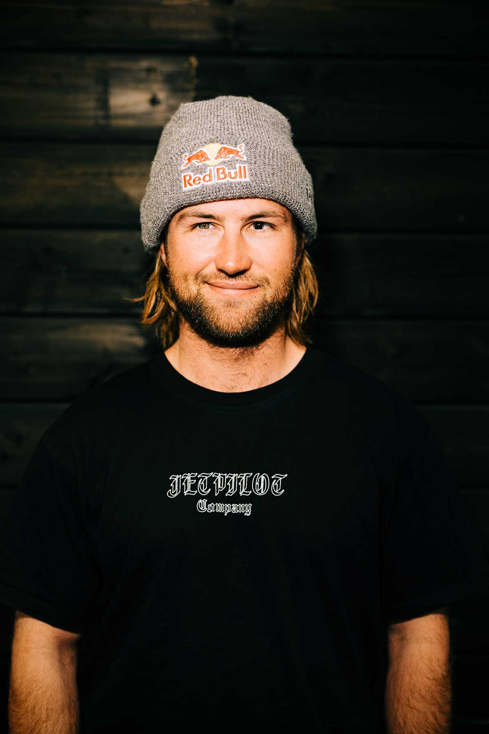 Man in gray beanie and black shirt smiling warmly.