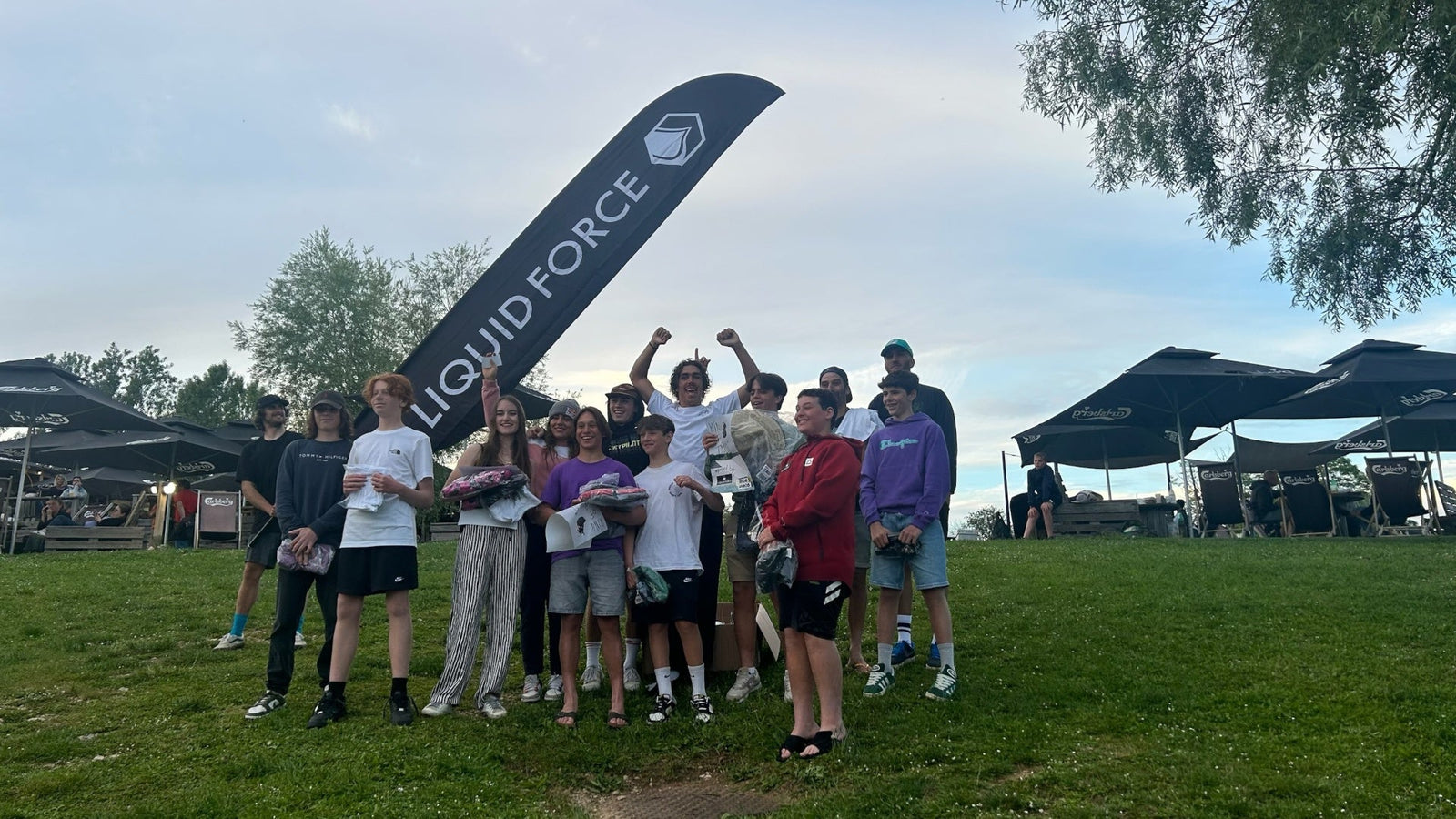 Several people standing side by side in front of a Liquid Force banner, all smiling and engaged in conversation.
