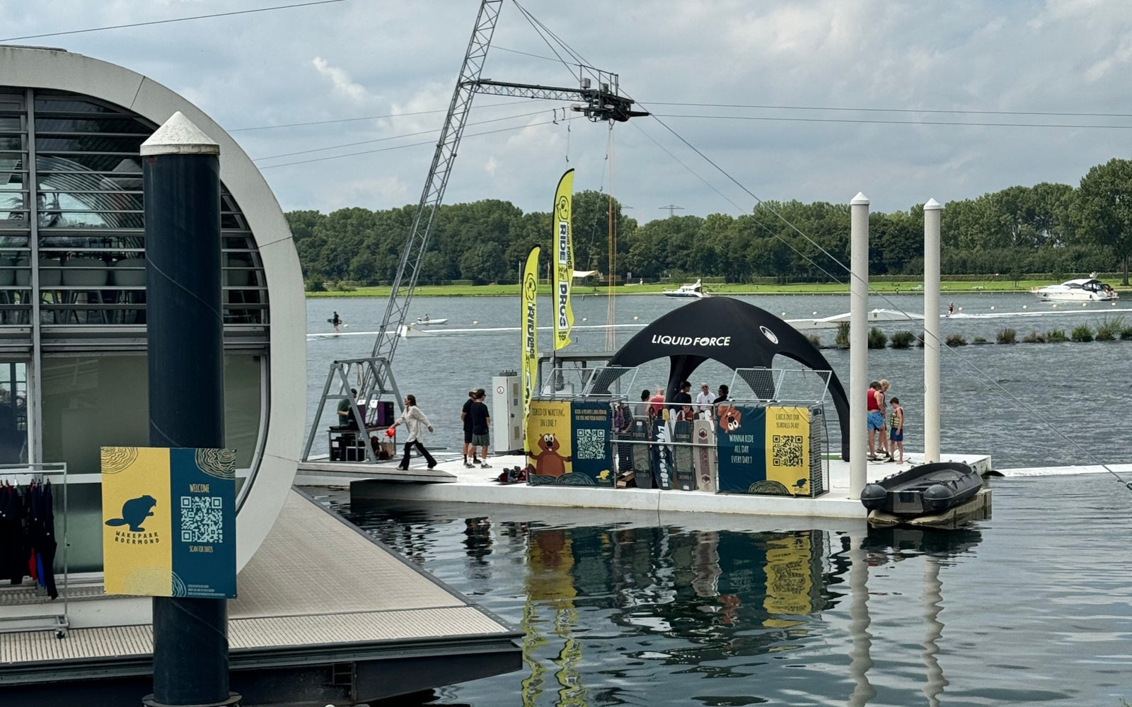 Liquid Force tent on dock with Ride With The Pros banners and lake view behind.