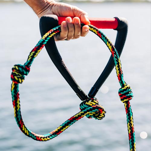 Close-up of hand holding colorful Liquid Force tow rope with red and black handle.