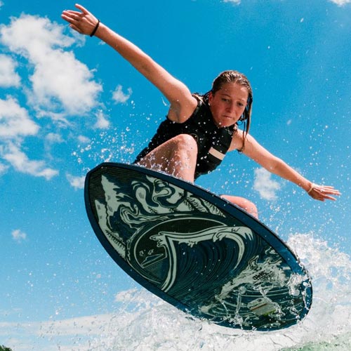Woman in life vest catching air on a wave with black and white Liquid Force wakesurf board.