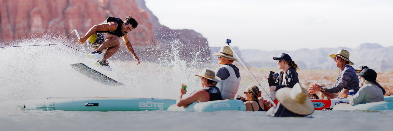 Wakeskater jumping over water float with other people watching from the water