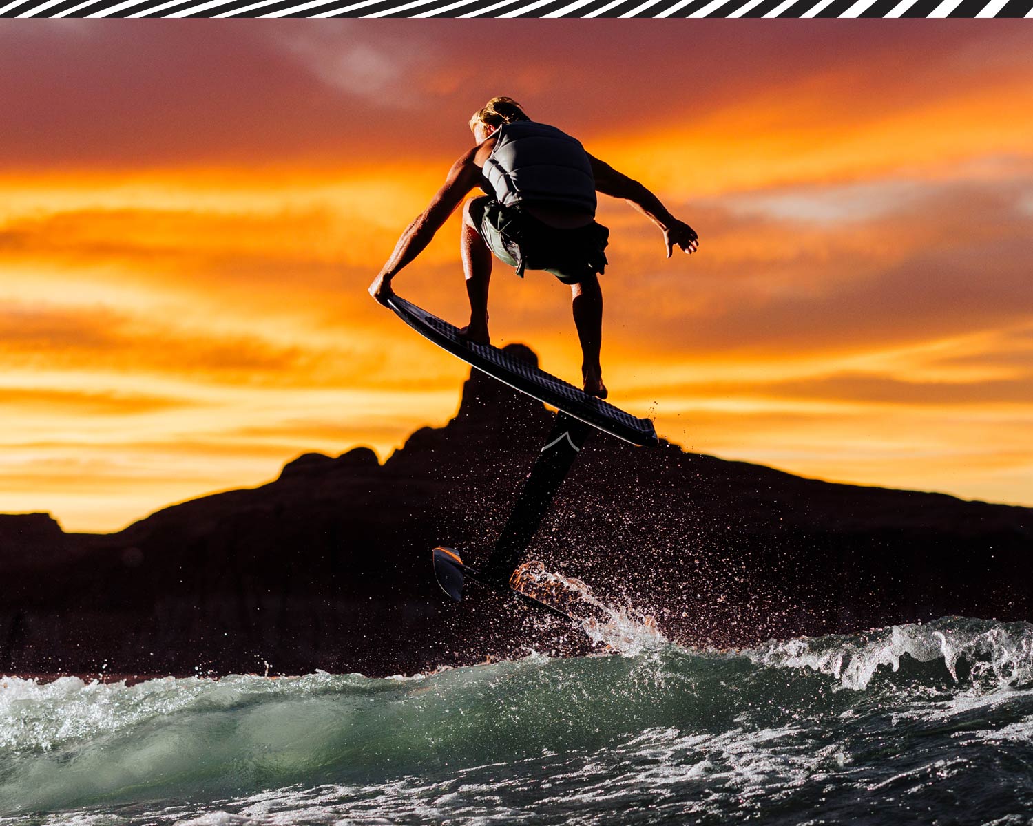 Person jumping on a foilboard with a vibrant sunset sky