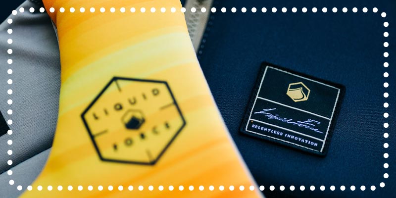 Close-up of Liquid Force logos on yellow and black fabric.