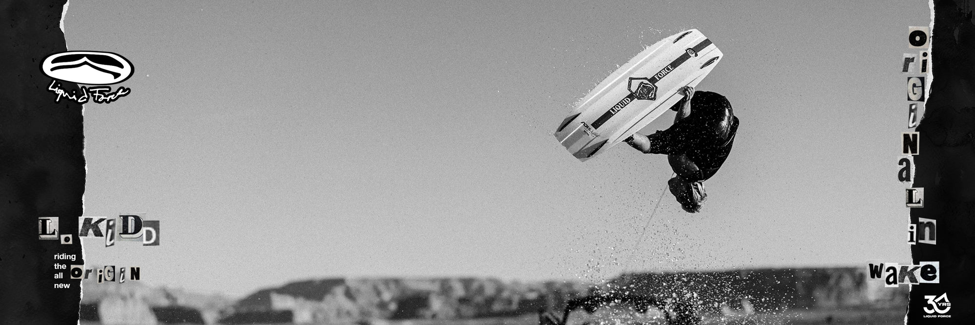 Black and white image of a wakeboarder performing a trick with cliffs of Lake Powell in the background.