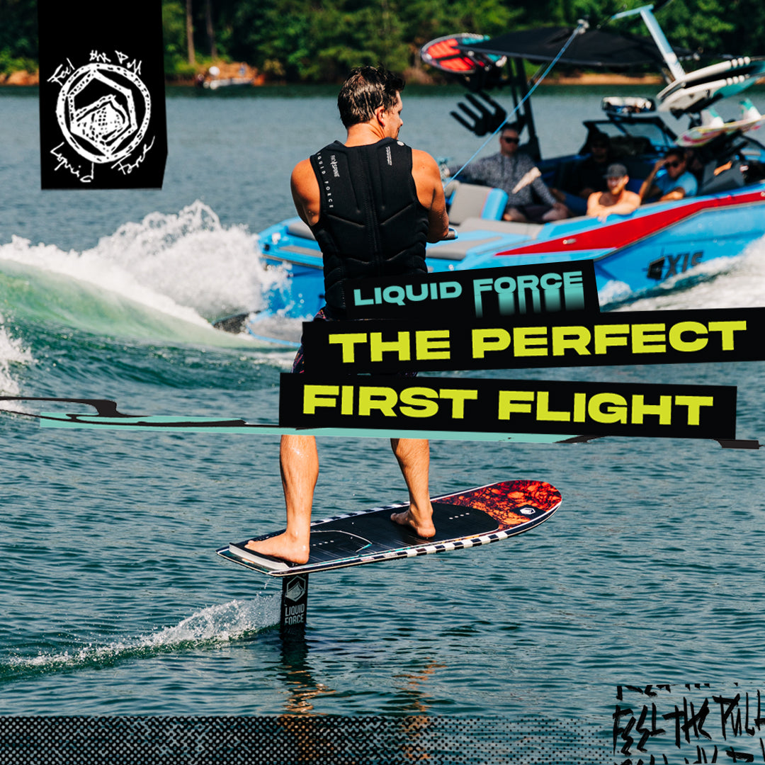 Liquid Force Launch Foil Board in action. Rider holding on to a rope while foiling on a foil board, behind a blue boat.