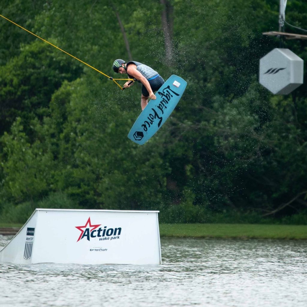Wakeboarder grabs board mid-air above a ramp at Action Wake Park.