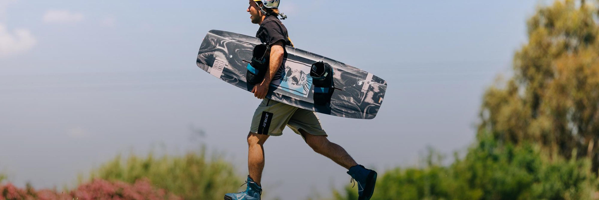 Liquid Force 4D Wakeboard Binding Collection - Closeup shot of LF Athlete Felix Georgii running with his wakeboard setup in hand while at a cable park.