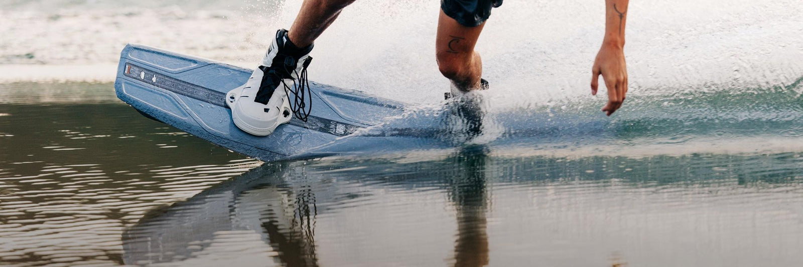 Liquid Force 6X Wakeboard Bindings Collection - Close up picture of LF Athlete Sam Brown riding his wakeboard on smooth water.