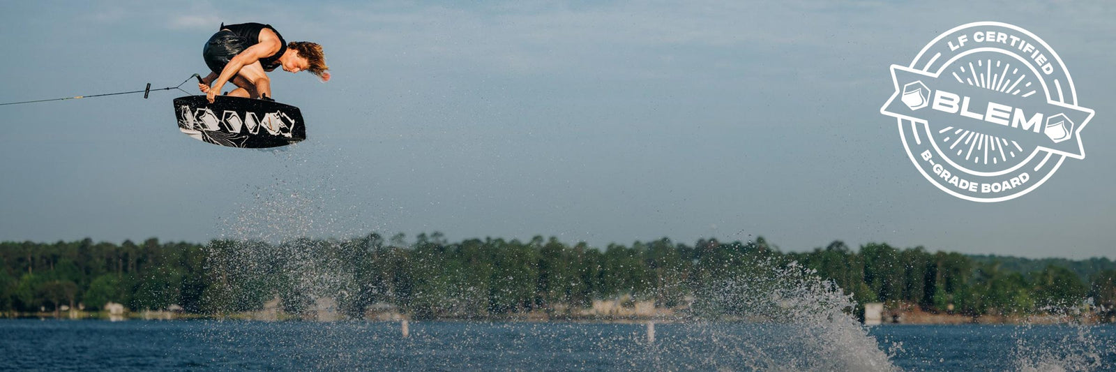 Liquid Force Blem Collection - LF Athlete Luca Kidd grabbing his board mid air behind a wakeboard boat.