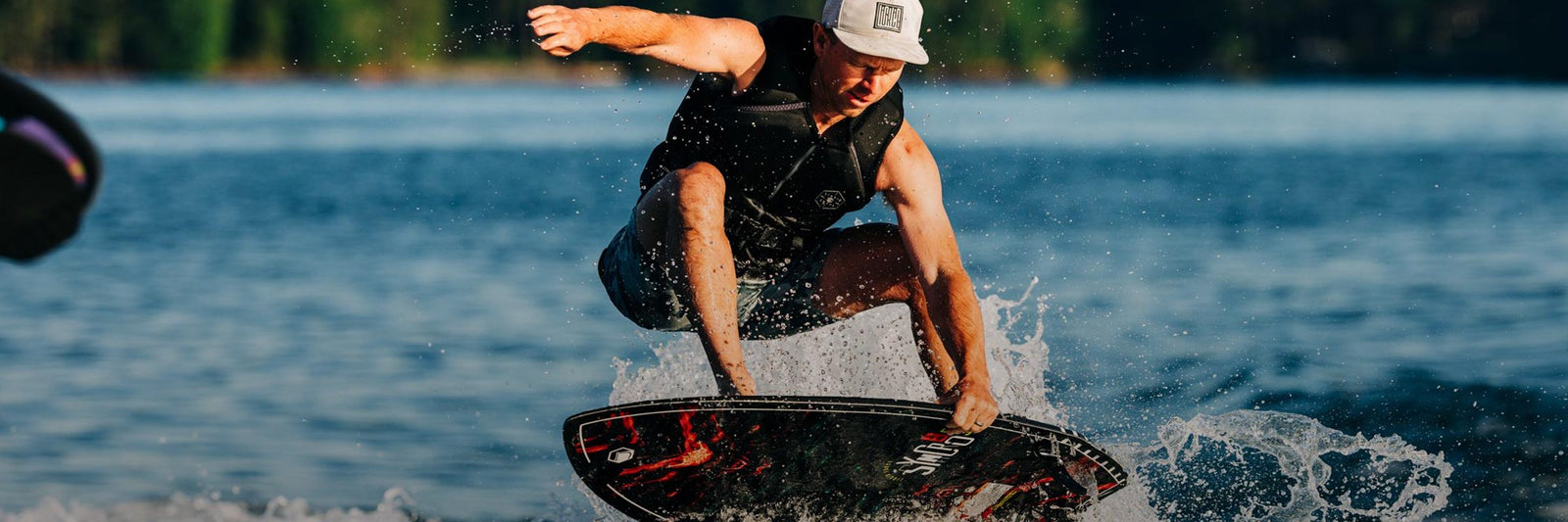 Liquid Force Crossover Wakesurf Collection - LF Athlete Tommy Czechin grabbing his wakesurf board mid air behind a boat.