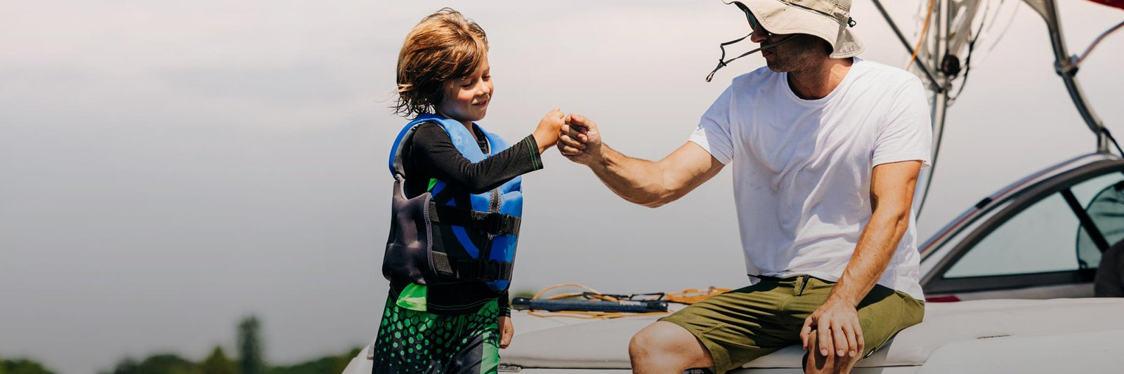 Liquid Force Kid's CGA Vest Collection - Son and father on the back of the boat, where son is in LF Kids CGA getting ready to ride.