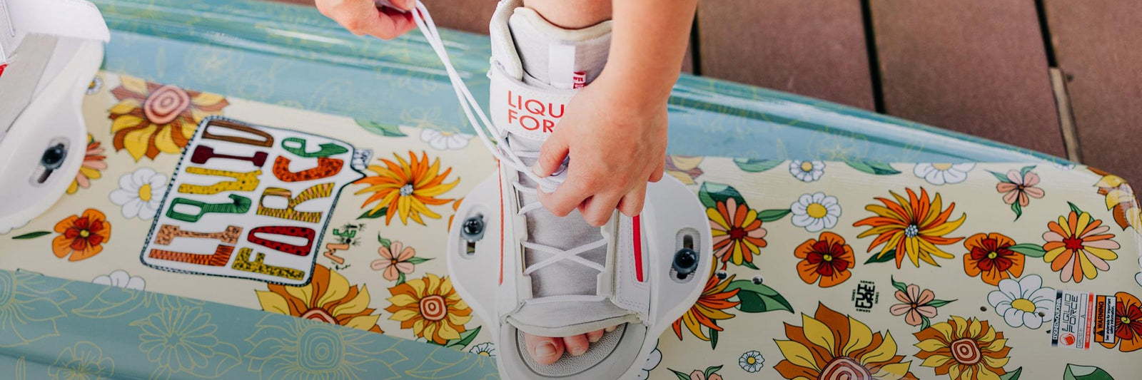 Liquid Force Kids Wakeboard Package - Closeup shot of younger rider lacing up her bindings on her wakeboard setup.