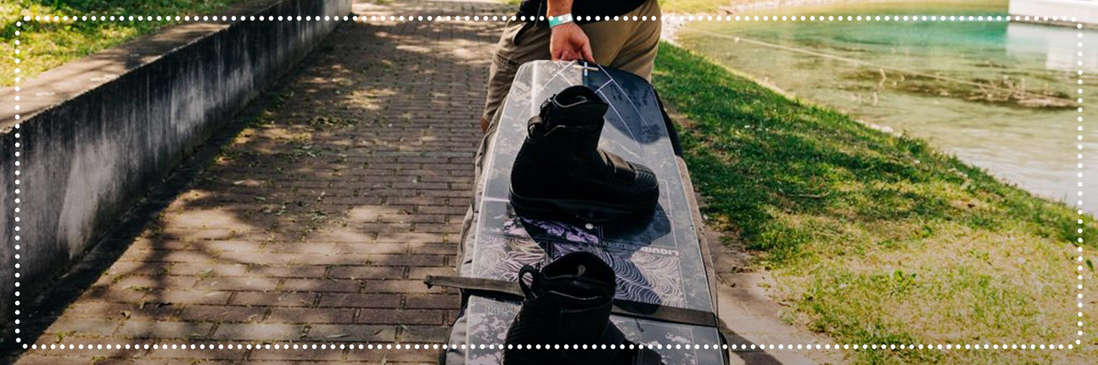 Liquid Force Clearance Bag Collection - Athlete walking down brick sidewalk with LF Rolling Gear Bag and Wakeboard Setup