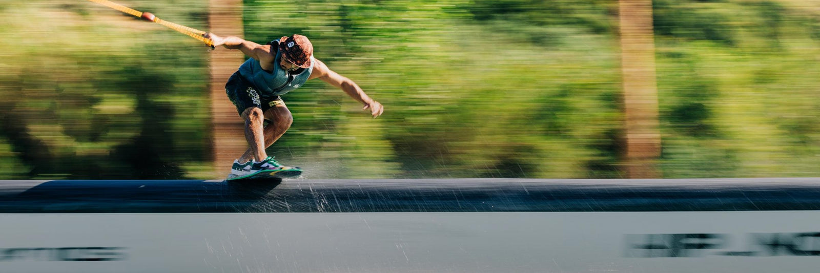 Liquid Force Wakeskate Collection - Closeup shot of LF Athlete Daniel Grant riding a wakeskate on a rail at a cable park.