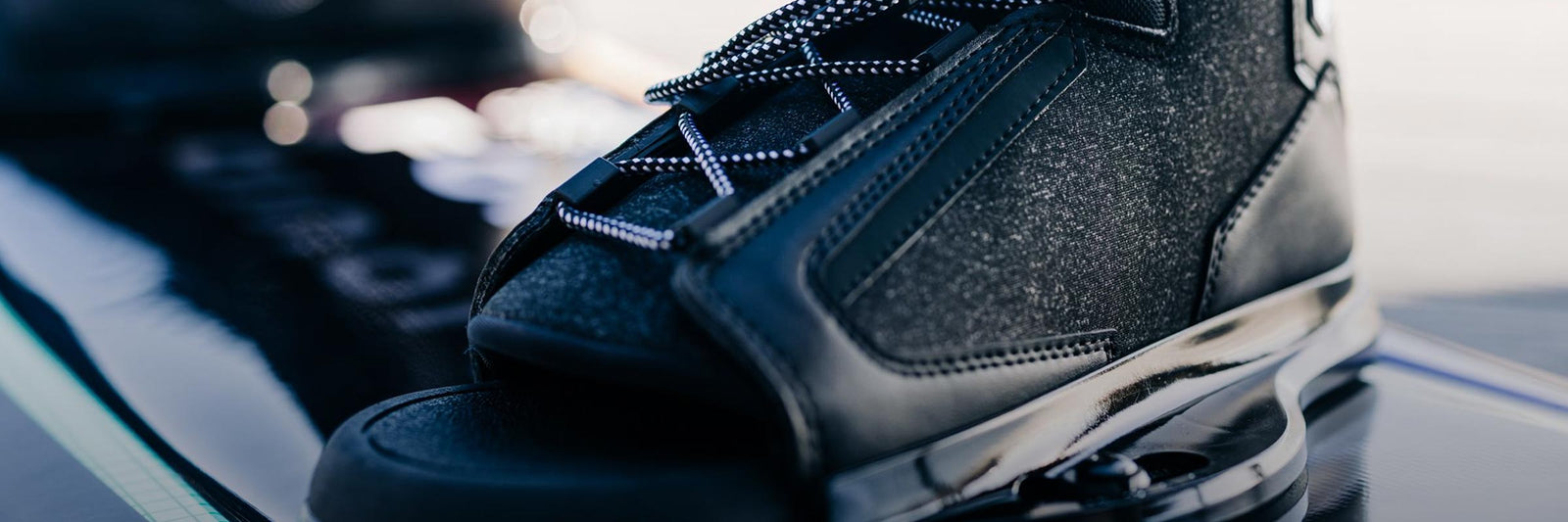 Close-up of a black 6R binding on a wakeboard.