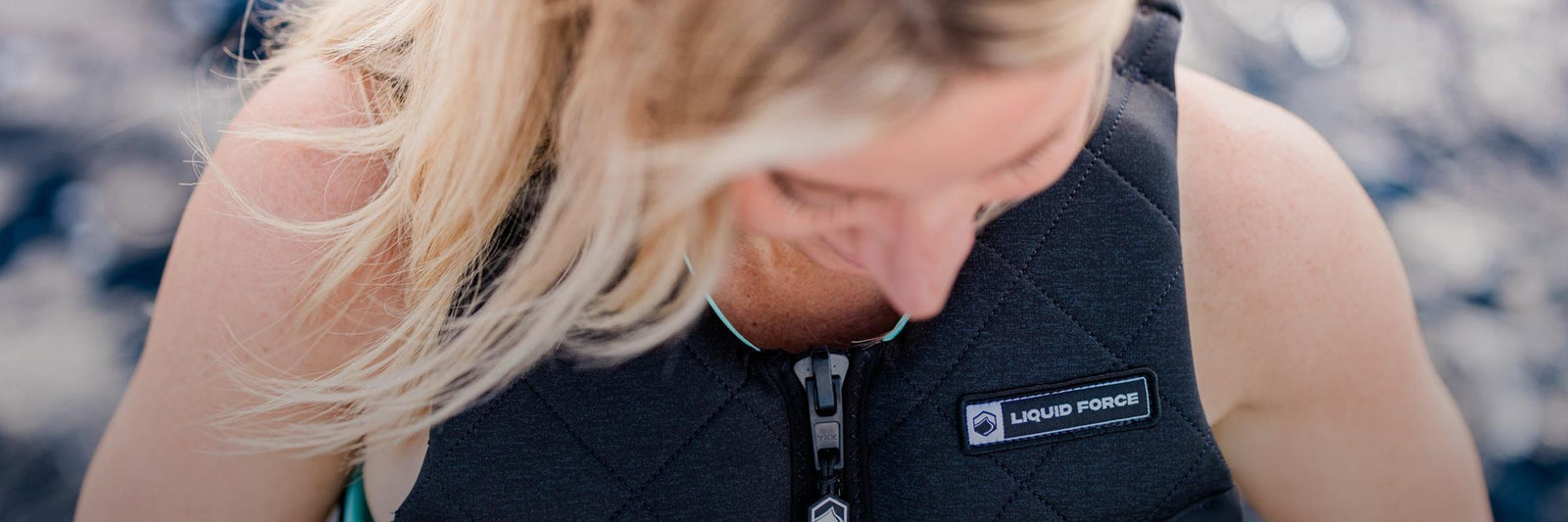 Close-up of a woman wearing a black life jacket with a visible Liquid Force logo patch.