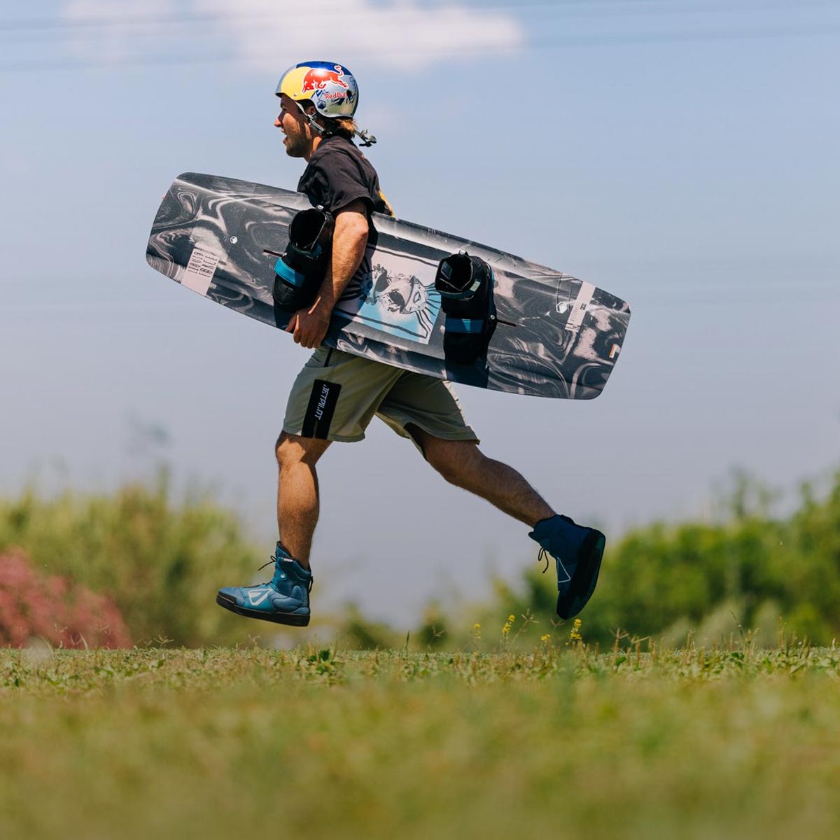 Liquid Force 4D Wakeboard Binding Collection - Closeup shot of LF Athlete Felix Georgii running with his wakeboard setup in hand while at a cable park.