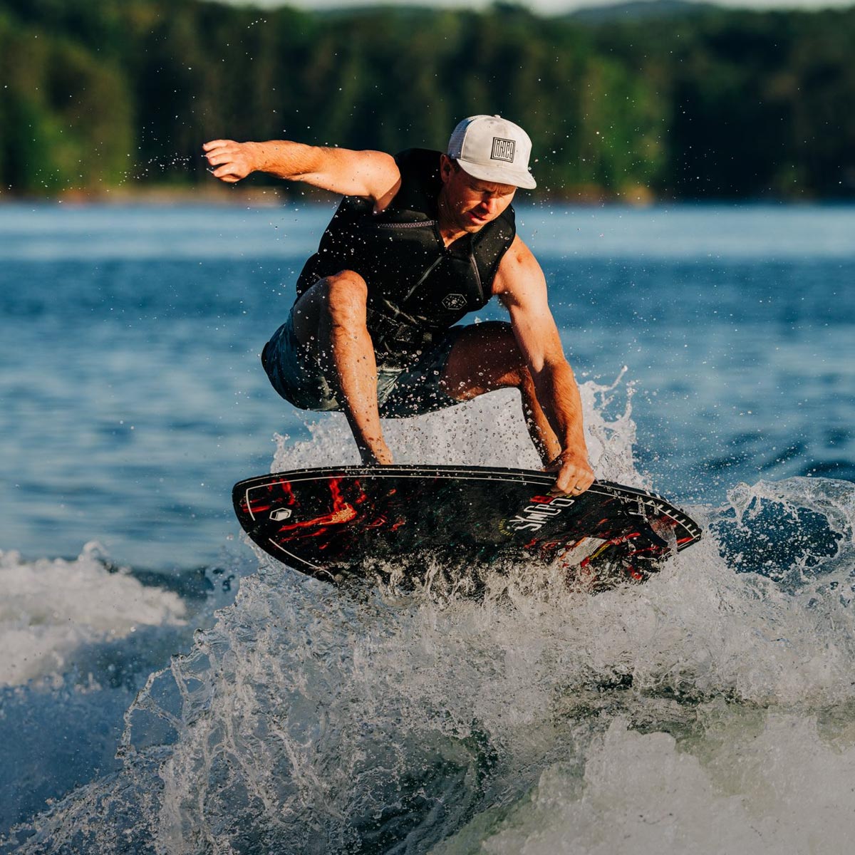 Liquid Force Crossover Wakesurf Collection - LF Athlete Tommy Czechin grabbing his wakesurf board mid air behind a boat.