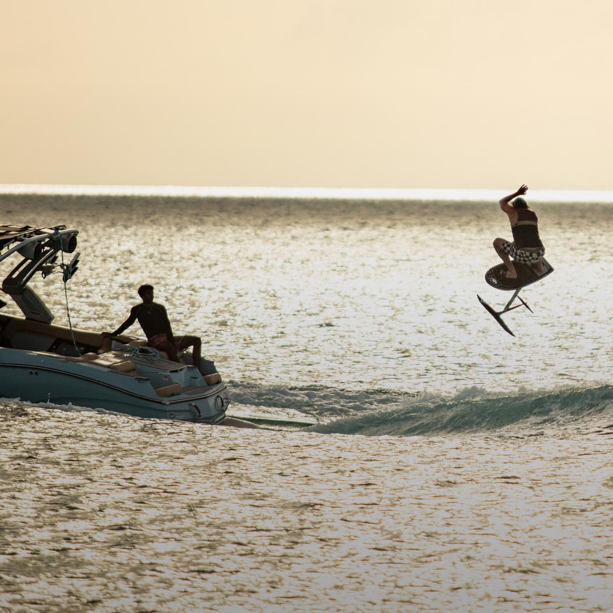 Liquid Force Foil Package Collection - Closeup shot of LF Athlete Harley Clifford doing an arial maneuver on a foil behind the boat at sunset.