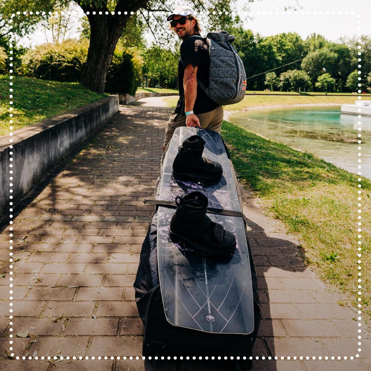 Liquid Force Clearance Bag Collection - Athlete walking down brick sidewalk with LF Rolling Gear Bag and Wakeboard Setup