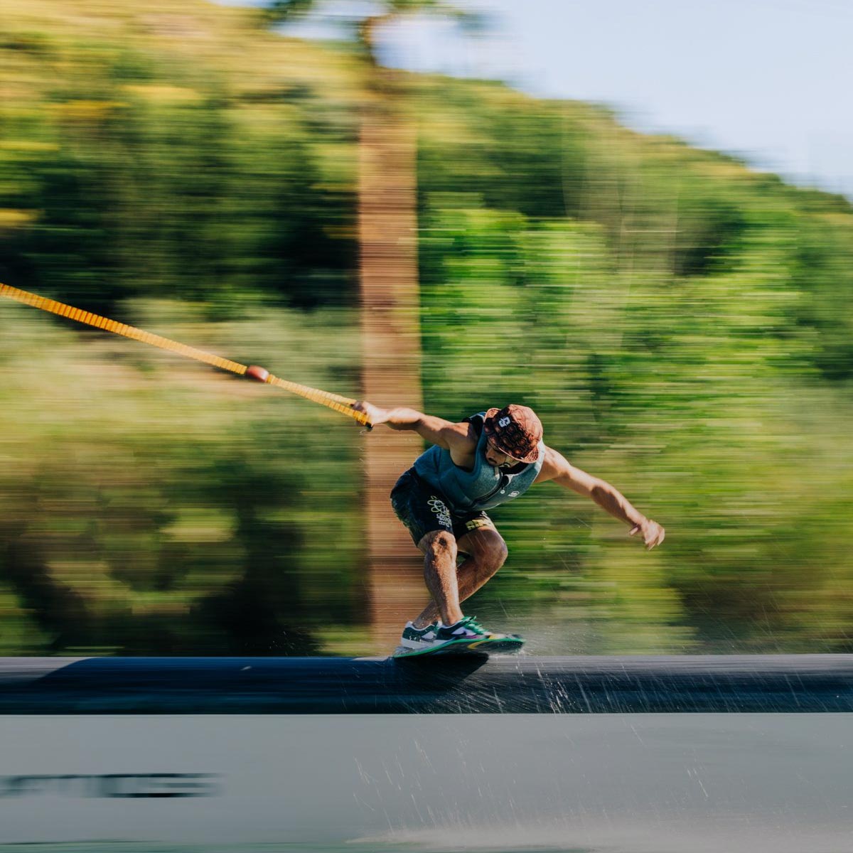 Liquid Force Wakeskate Collection - Closeup shot of LF Athlete Daniel Grant riding a wakeskate on a rail at a cable park.