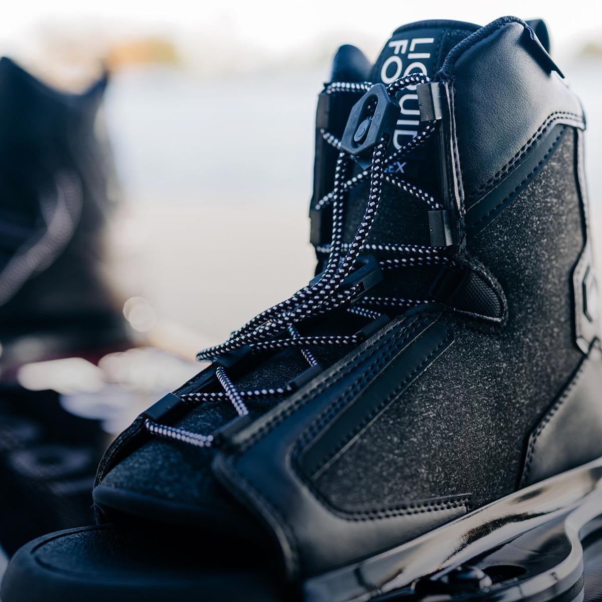 Close-up of a black 6R binding on a wakeboard.