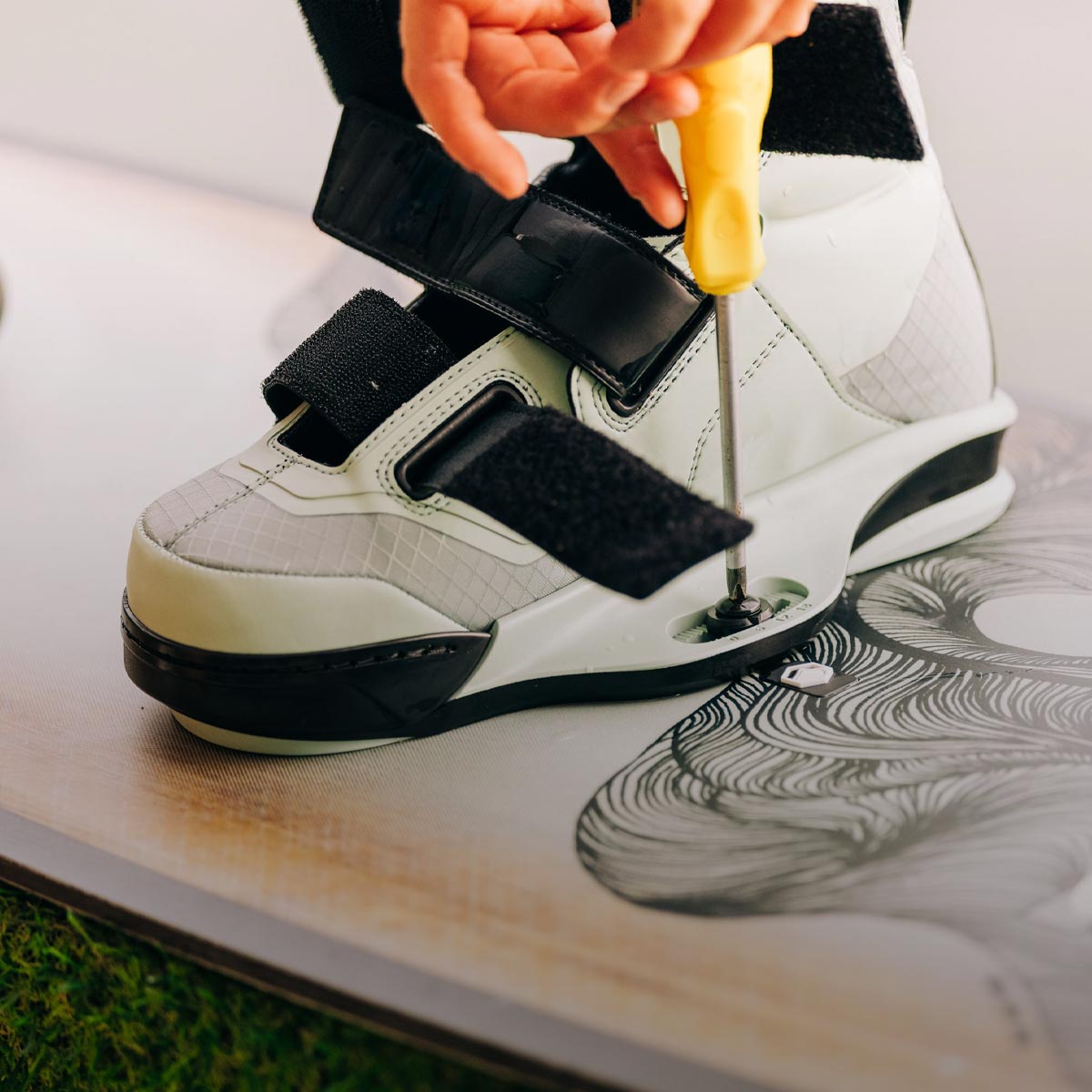 Close-up of a 6X binding being mounted onto a wakeboard.