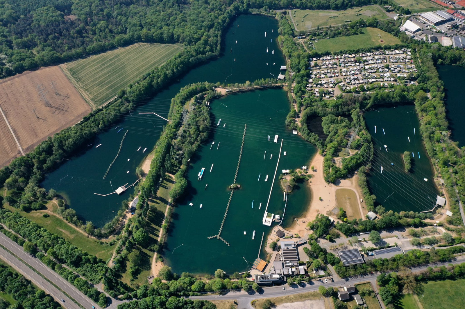Aerial view of a large wake park with multiple lakes, obstacles, and surrounding forest.