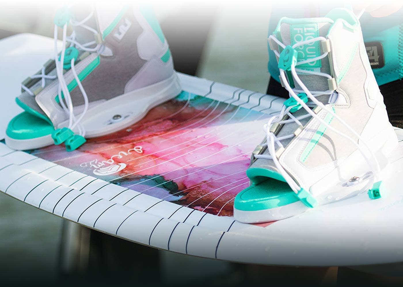 Teal boots on a colorful wakeboard with stripes.