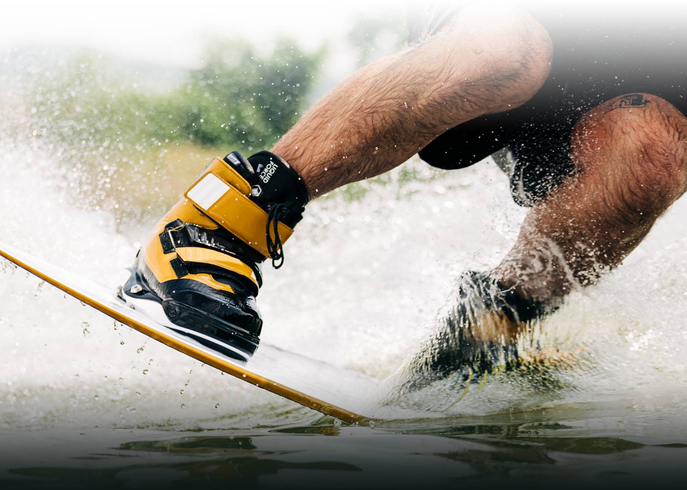 Splashy close-up of a person wakeboarding on glistening water.