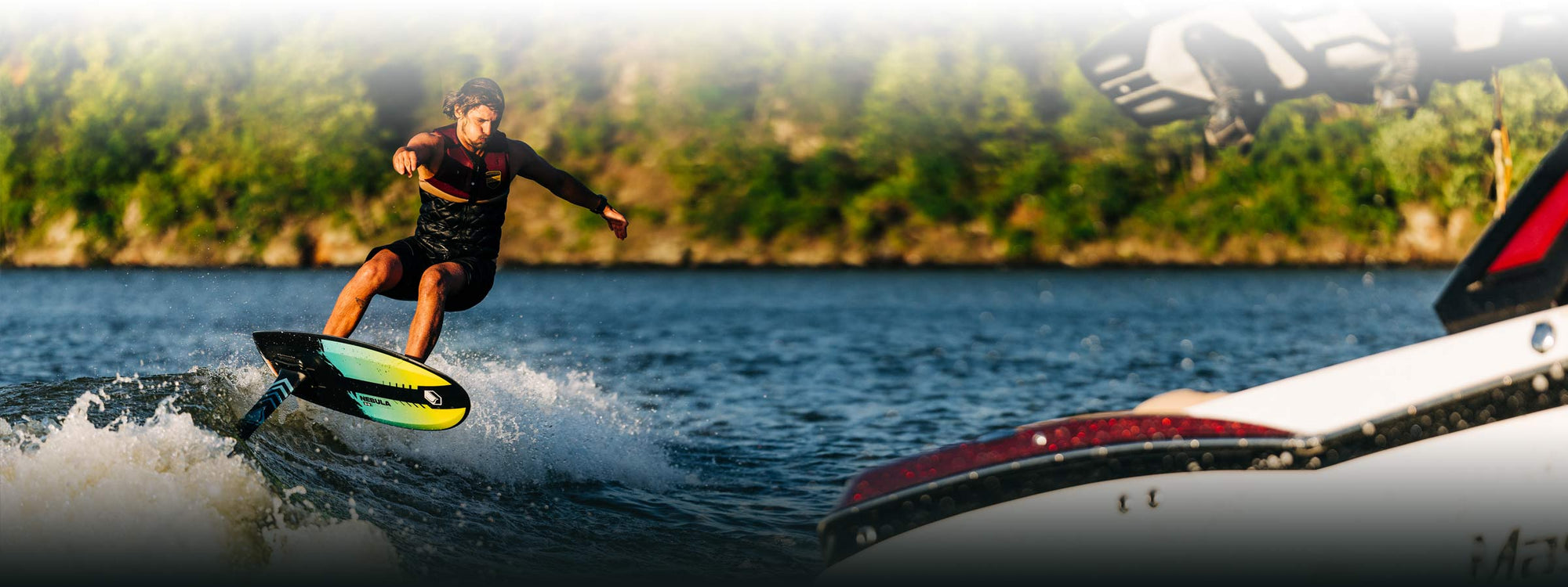 Wakesurfing on a foil board behind a boat on a bright, sunny day.