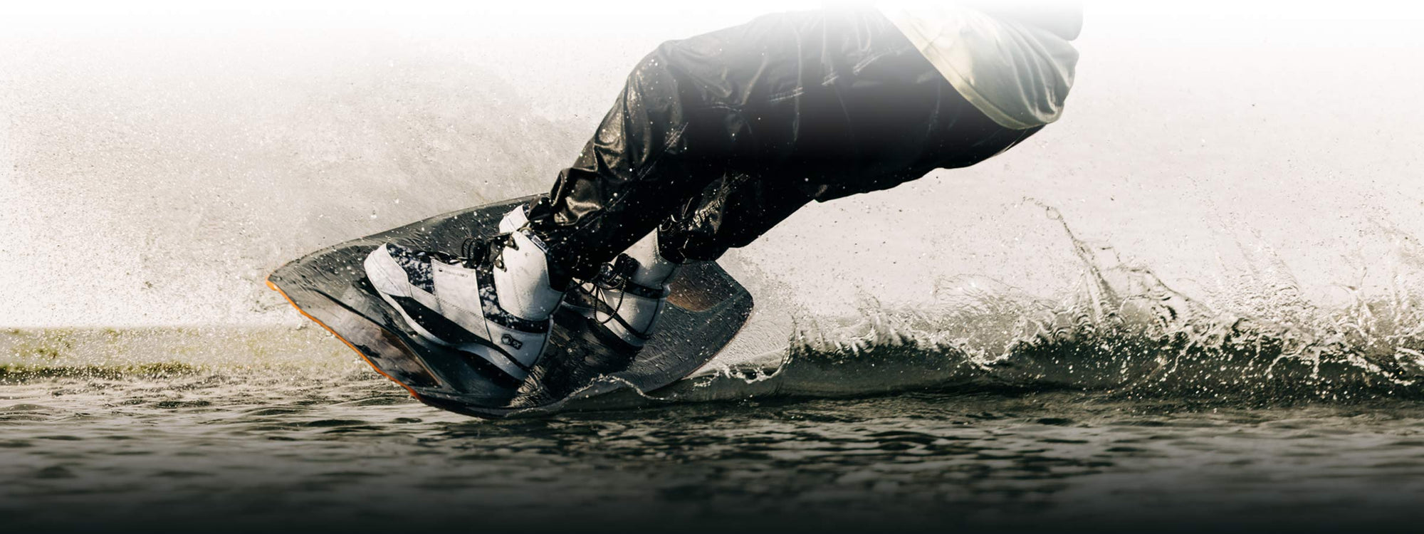 Close-up of a person wakeboarding, water bursting around their agile feet.
