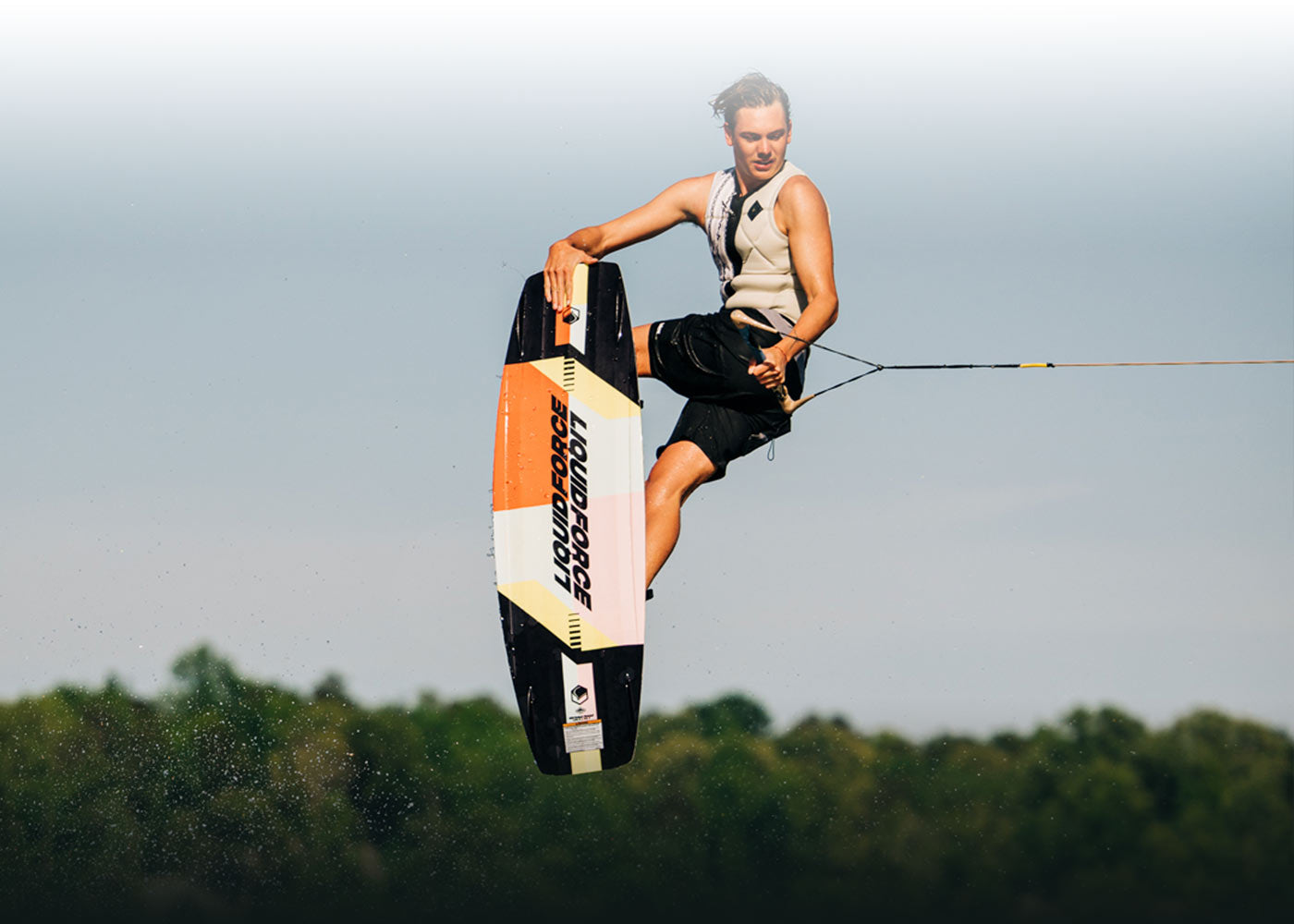 Person wakeboarding in mid-air against a cloudy sky.