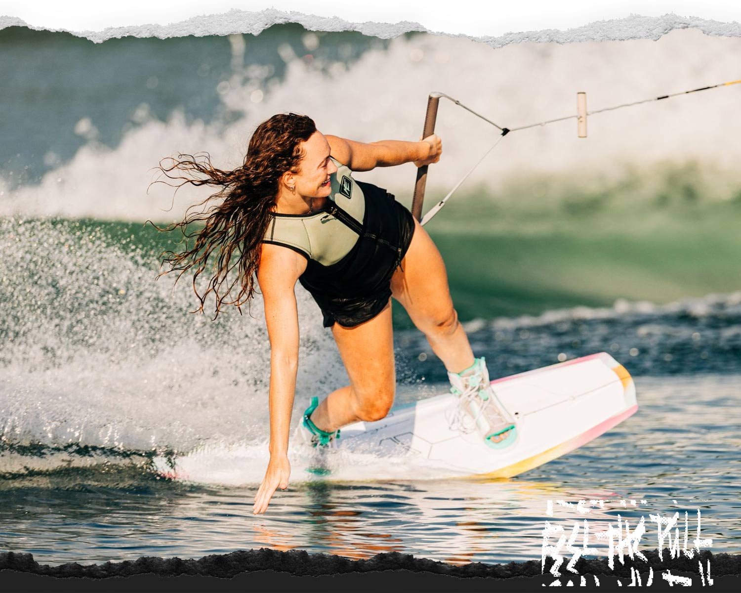 Female rider edges with spray behind her, hair flying.