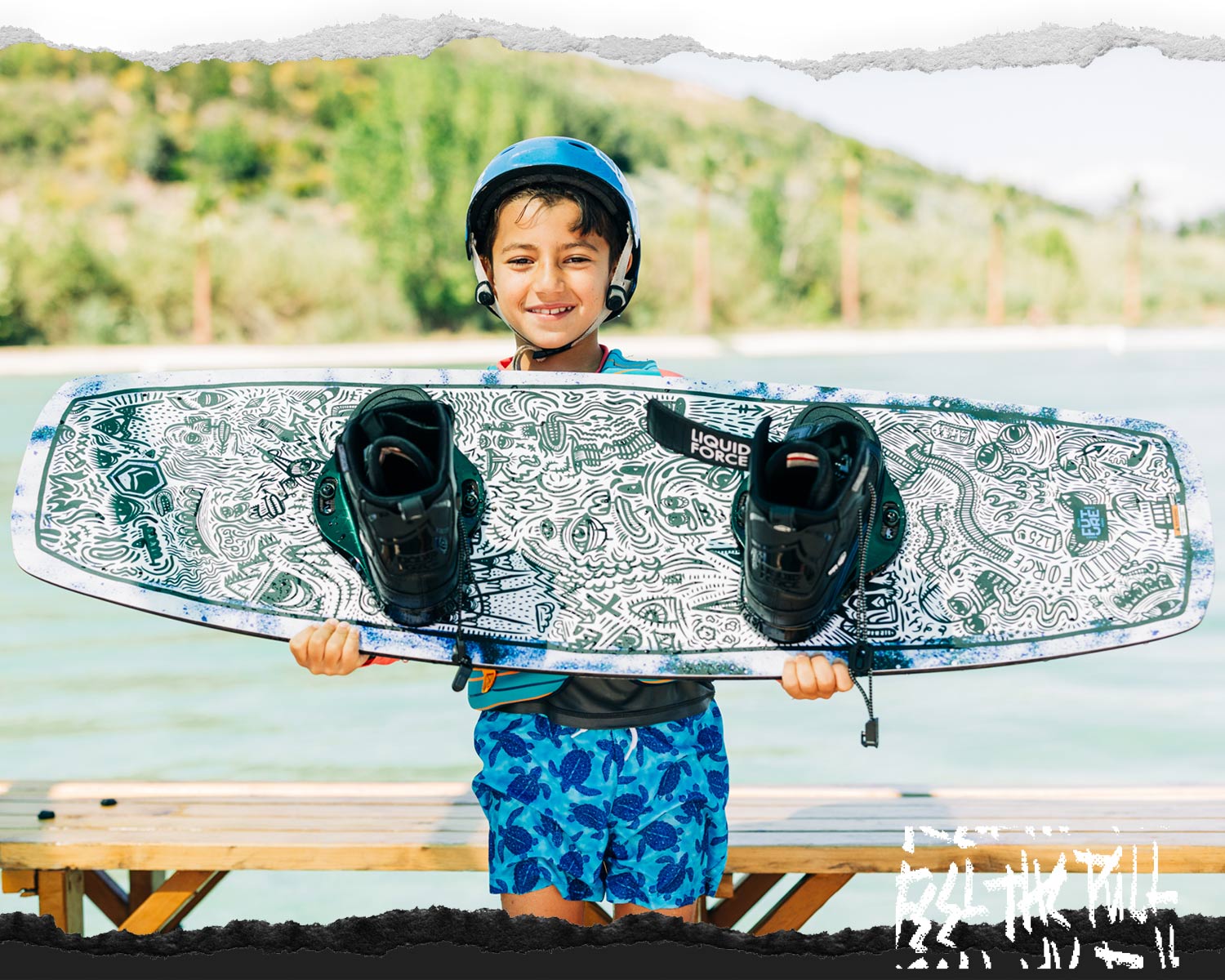 Smiling child holds a Liquid Force APEX FS wakeboard with black boots and a doodle-style design.