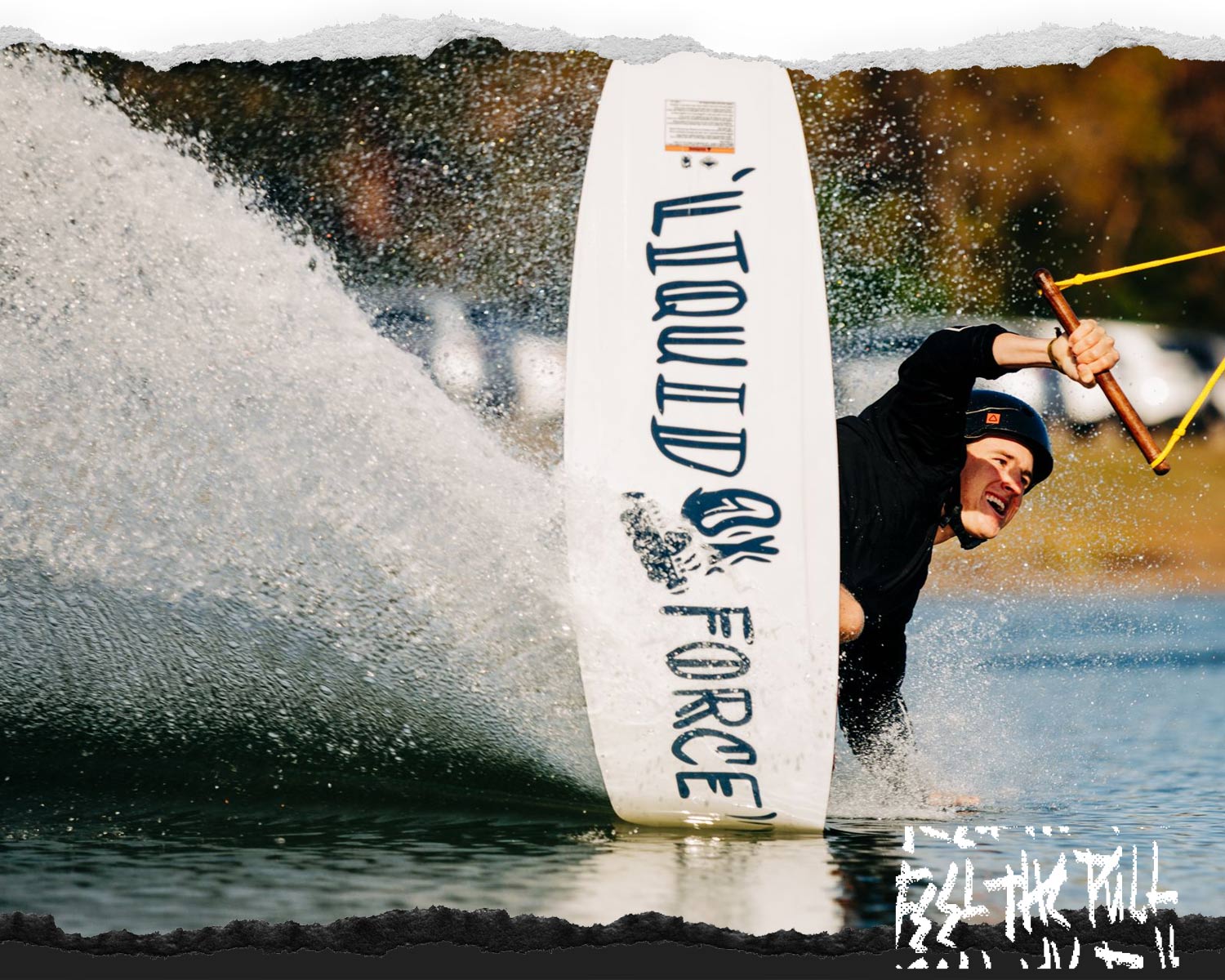 Wakeboarder carving through the water while holding the rope (Liquid Force brand visible).