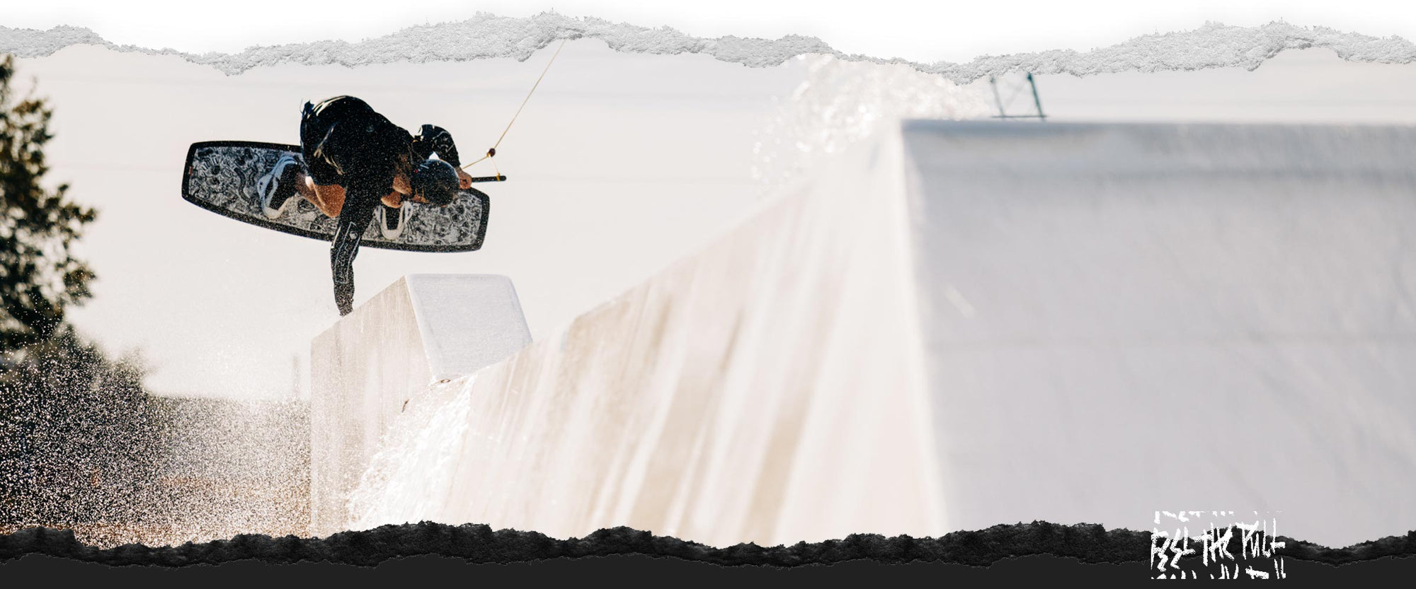 Wakeboarder executing a trick on a rail with water splashing around.