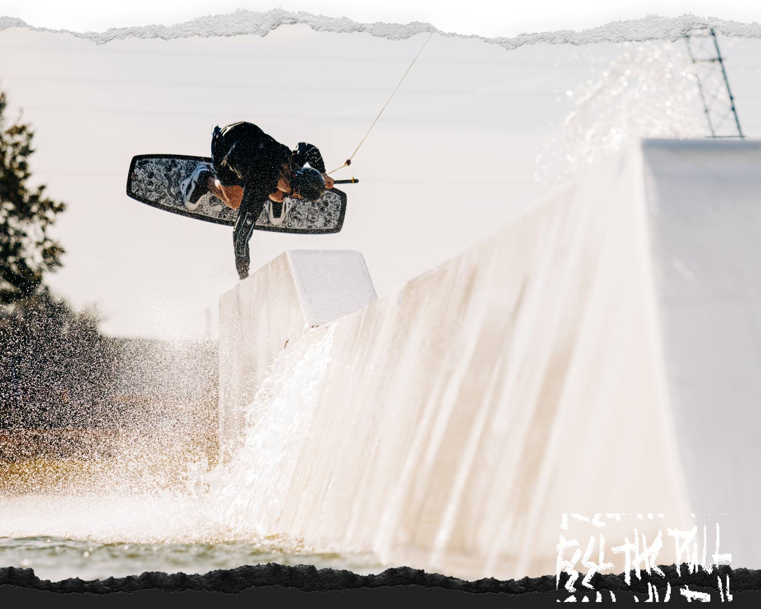 Wakeboarder executing a trick on a rail with water splashing around.