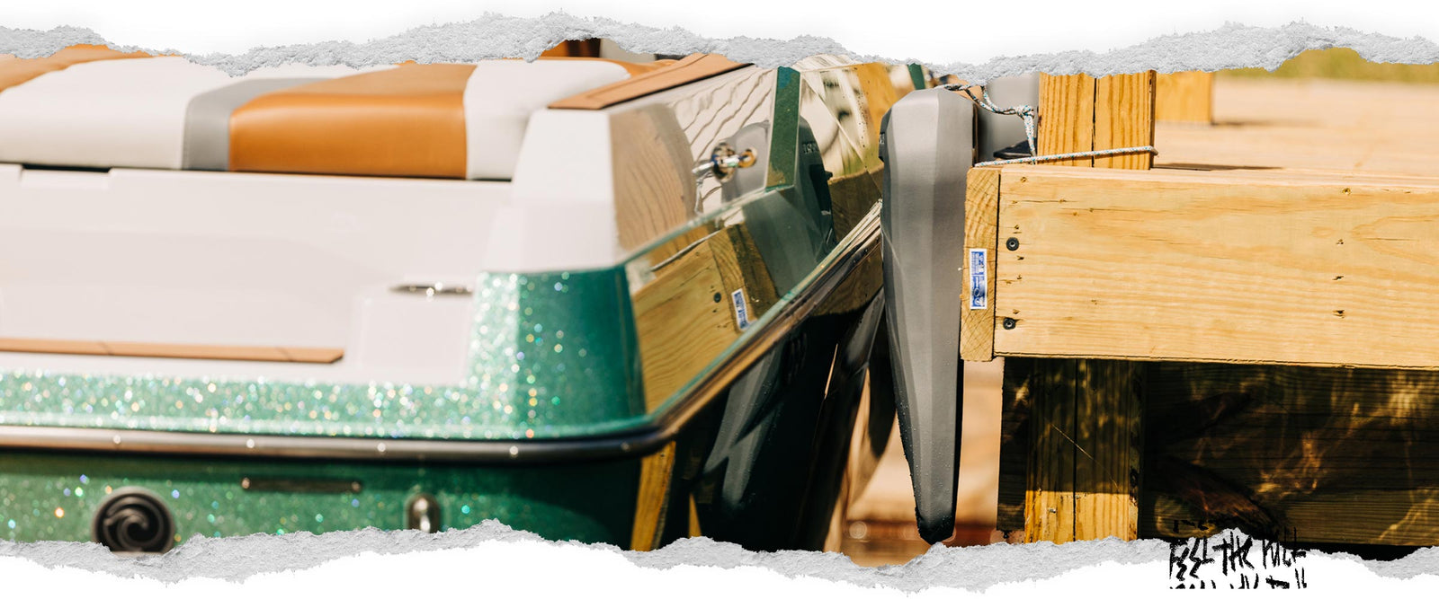 Dark grey Liquid Force boat defender protecting docked boat from wooden dock.