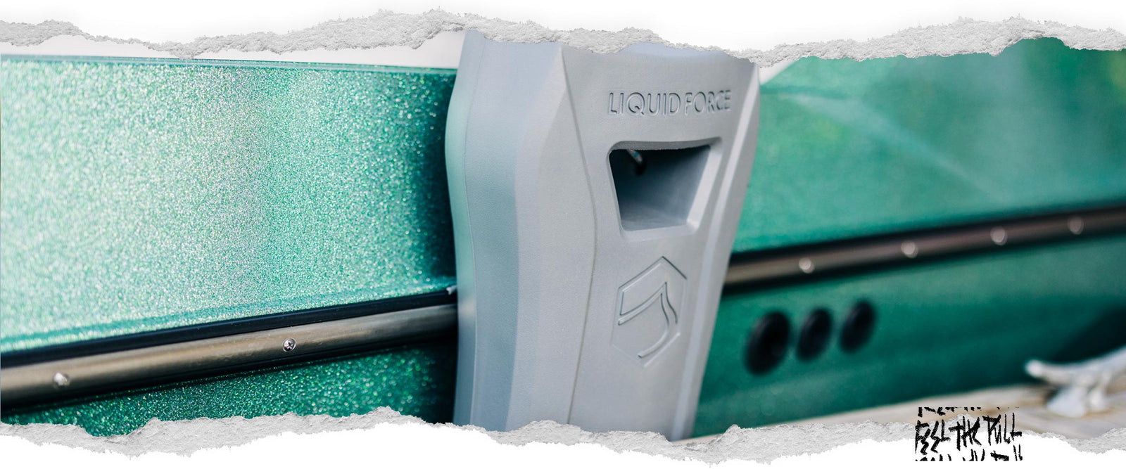 Light grey Liquid Force boat defender on metallic green hull of wake boat.