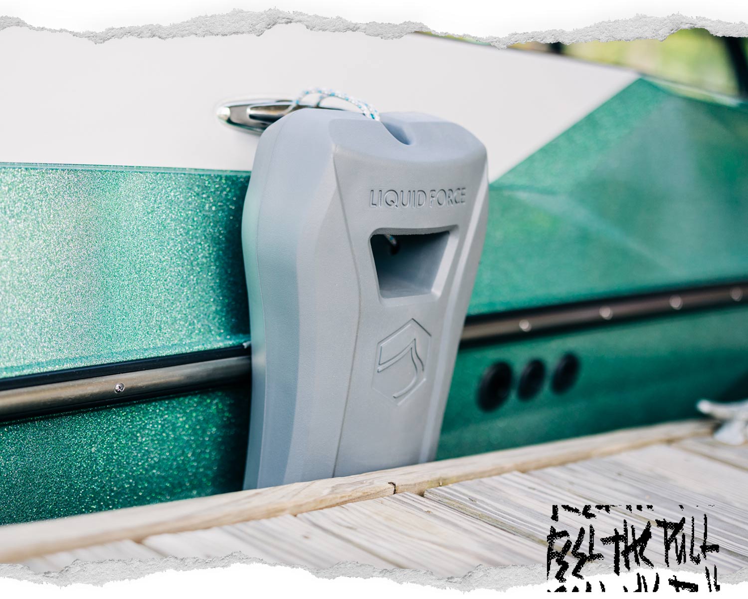 Light grey Liquid Force boat defender on metallic green hull of wake boat.