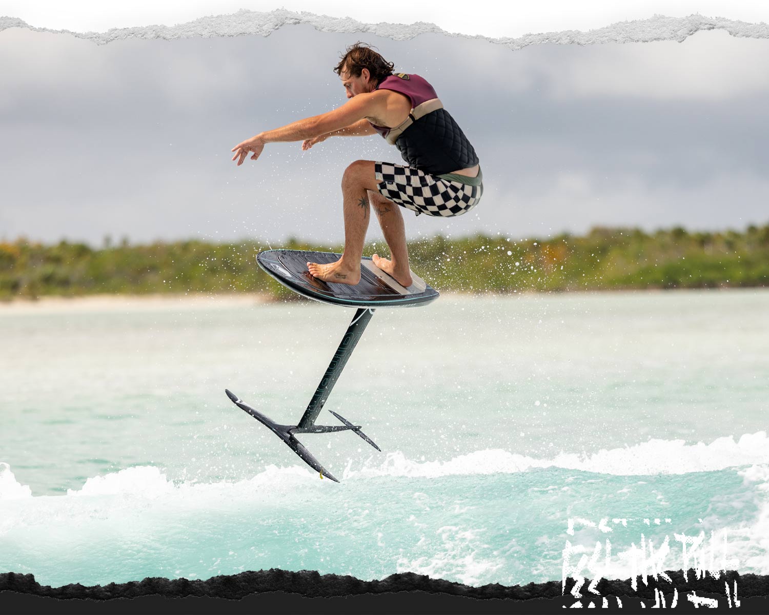 Man rides a black foil board above turquoise water, wearing checkered shorts.