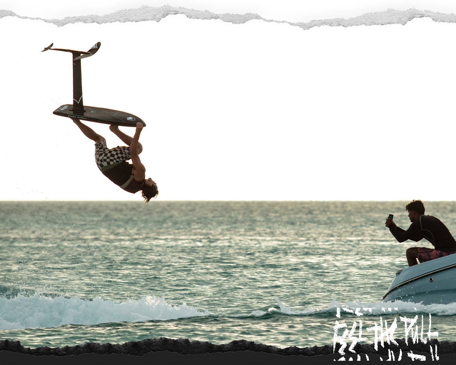 Foil boarder does a flip above the water as another person films from a boat.