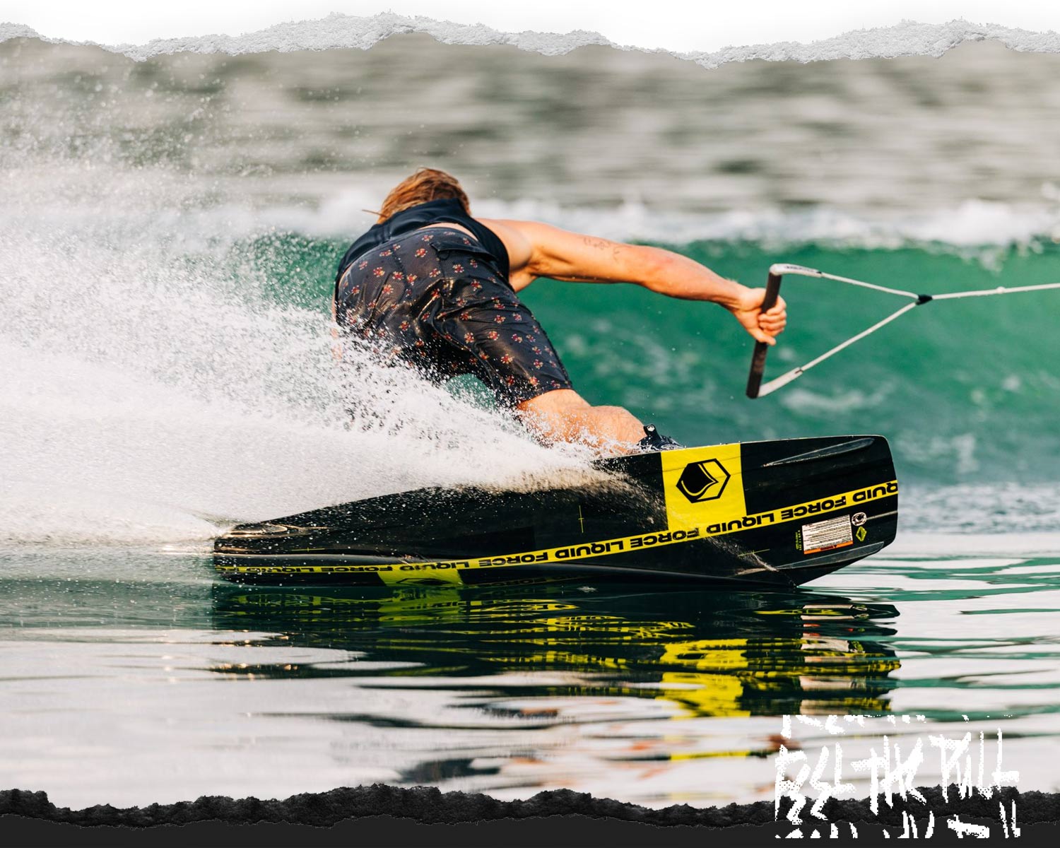 Wakeboarder in floral shorts carves hard turn on black and yellow Liquid Force board.