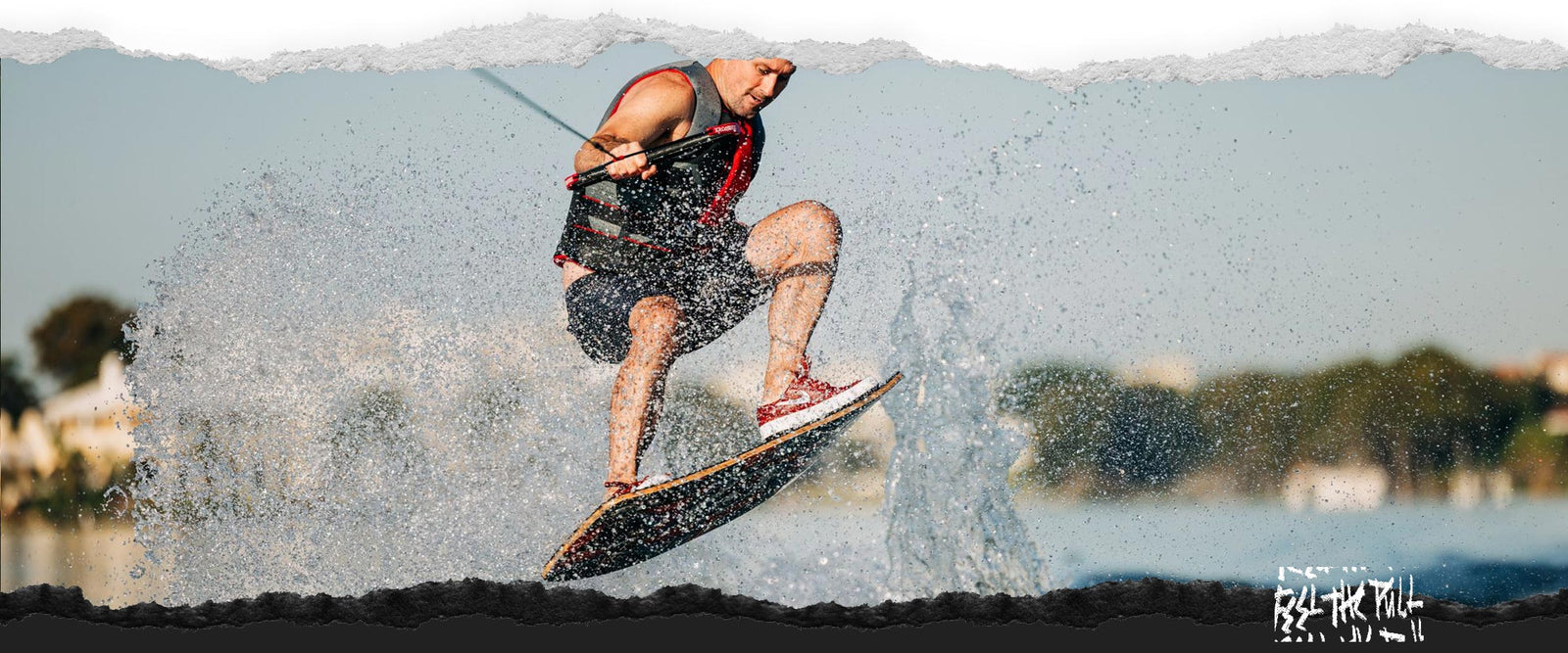 Rider jumping on the Liquid Force Focus Wakeskate in a red and gray vest.