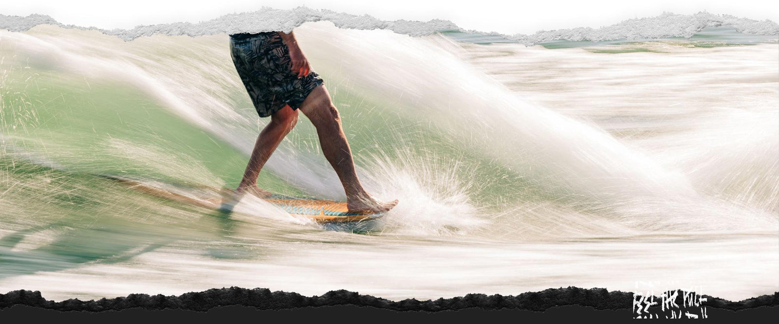 Rider in blue vest carving on a wave on a light wood wakesurf board with green water spray.
