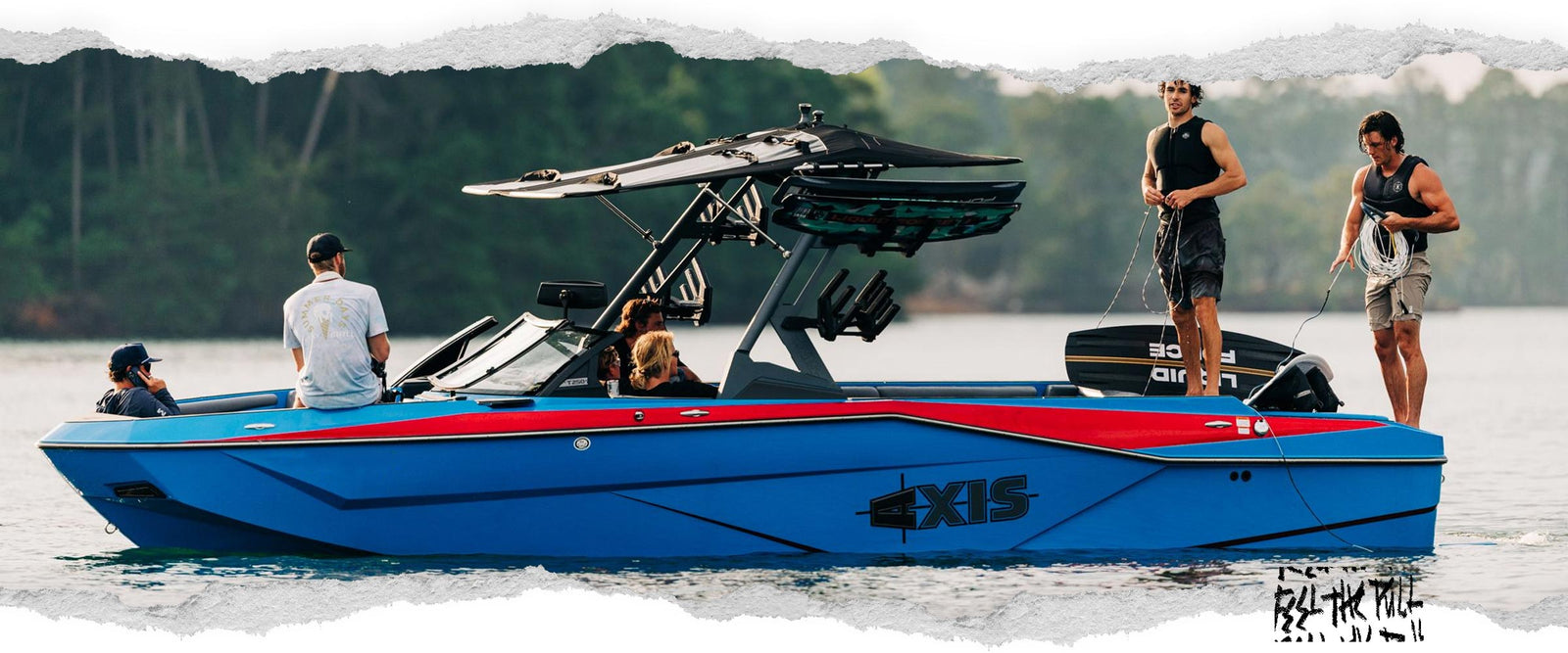 Cinco personas a bordo y alrededor de un barco Axis azul y rojo, dos de ellas de pie con cuerdas en la cubierta trasera.