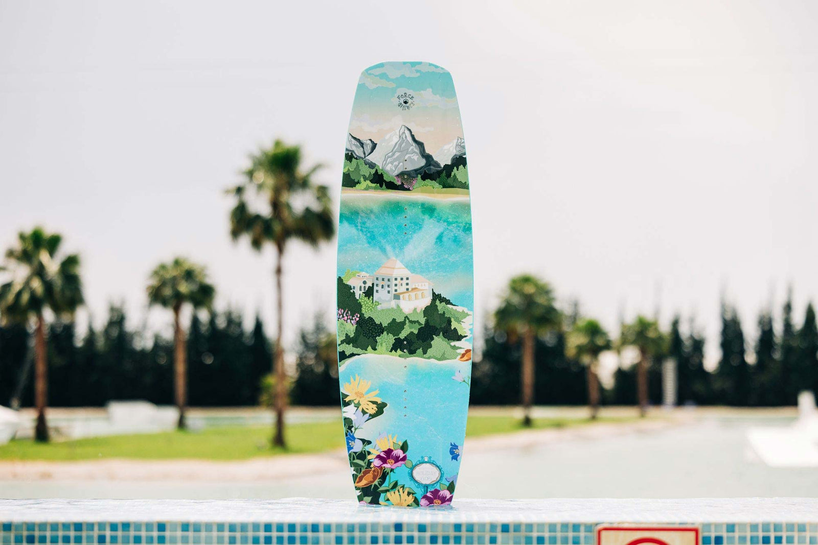 Picture of a the Liquid Force Holiday Wakeboard standing upright next to water's edge.